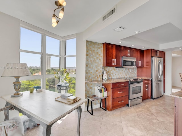 kitchen featuring backsplash, a raised ceiling, light stone countertops, and appliances with stainless steel finishes