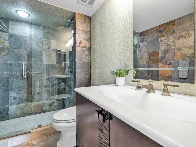 bathroom with an enclosed shower, vanity, toilet, and tile walls