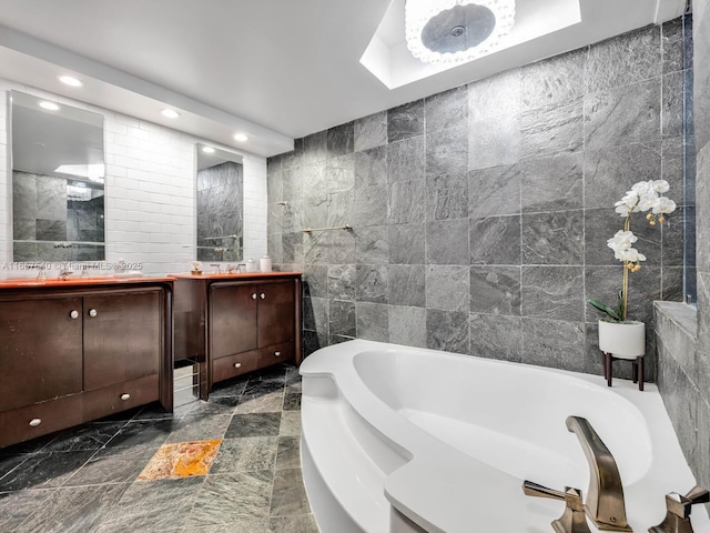 bathroom with vanity, a tub to relax in, and tile walls