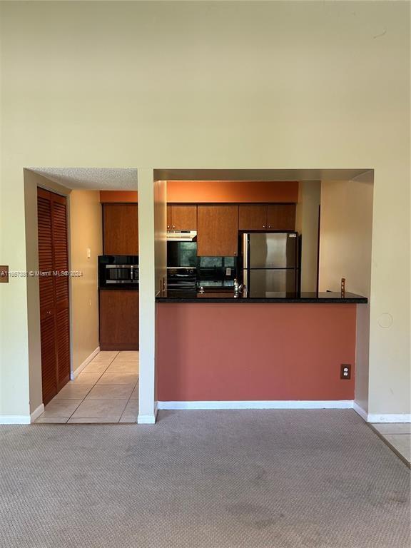 kitchen featuring appliances with stainless steel finishes, light colored carpet, and kitchen peninsula