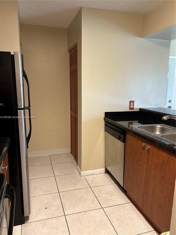 kitchen featuring light tile patterned floors, stainless steel appliances, a textured ceiling, and sink