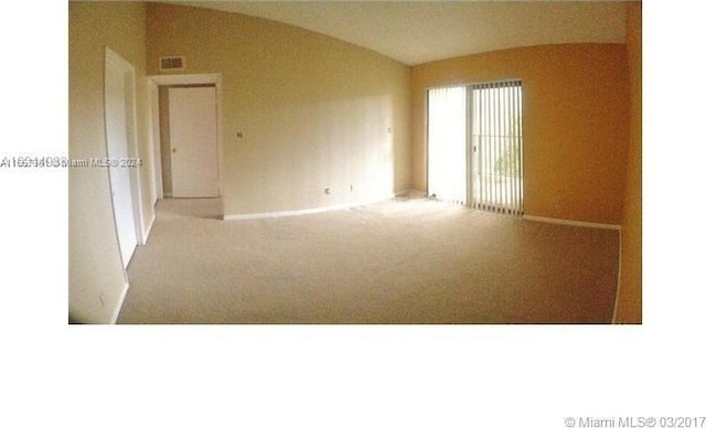 carpeted empty room featuring lofted ceiling