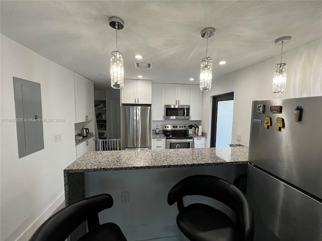 kitchen featuring a breakfast bar area, stainless steel appliances, kitchen peninsula, white cabinetry, and electric panel