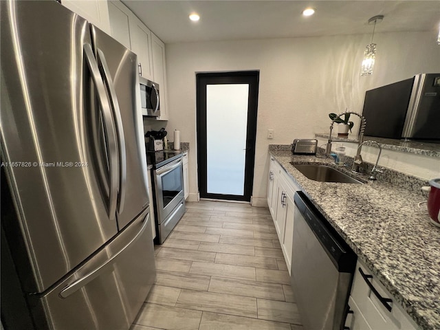 kitchen with stone countertops, appliances with stainless steel finishes, light hardwood / wood-style floors, sink, and white cabinetry