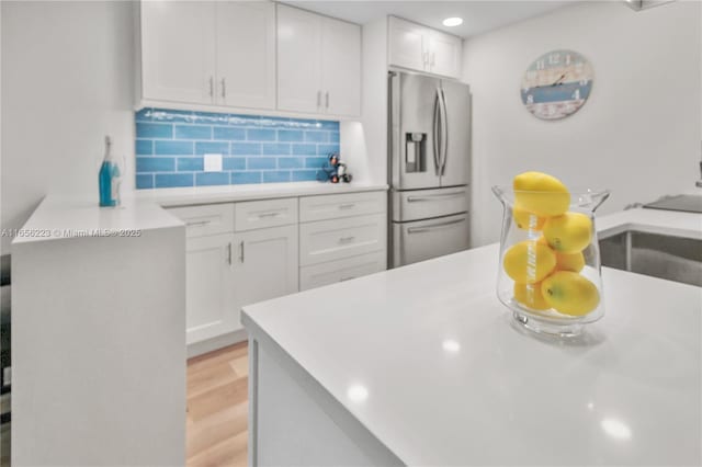 kitchen with white cabinetry, decorative backsplash, stainless steel fridge with ice dispenser, and light hardwood / wood-style flooring