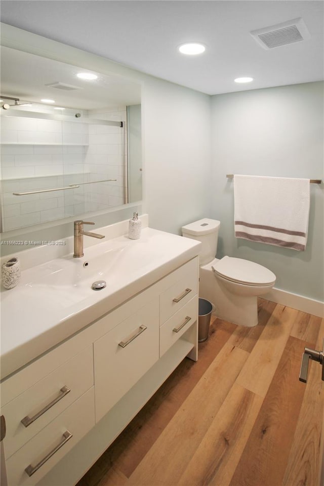 bathroom featuring a shower, toilet, vanity, and hardwood / wood-style flooring