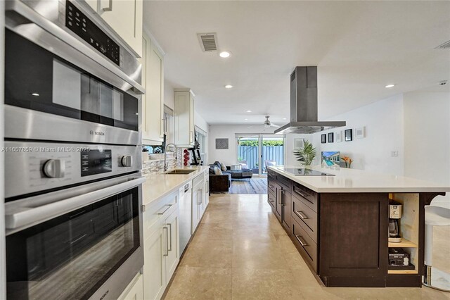 kitchen with dark brown cabinets, stainless steel double oven, white cabinetry, and island exhaust hood