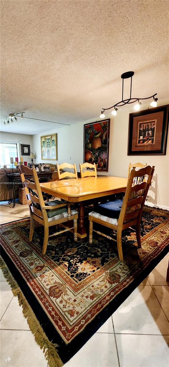 tiled dining space featuring track lighting and a textured ceiling