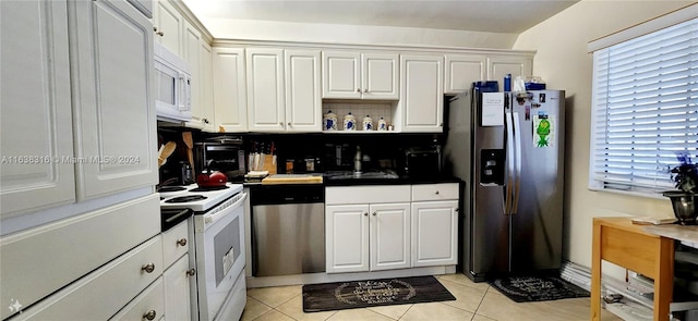 kitchen with appliances with stainless steel finishes, white cabinetry, light tile patterned floors, and sink