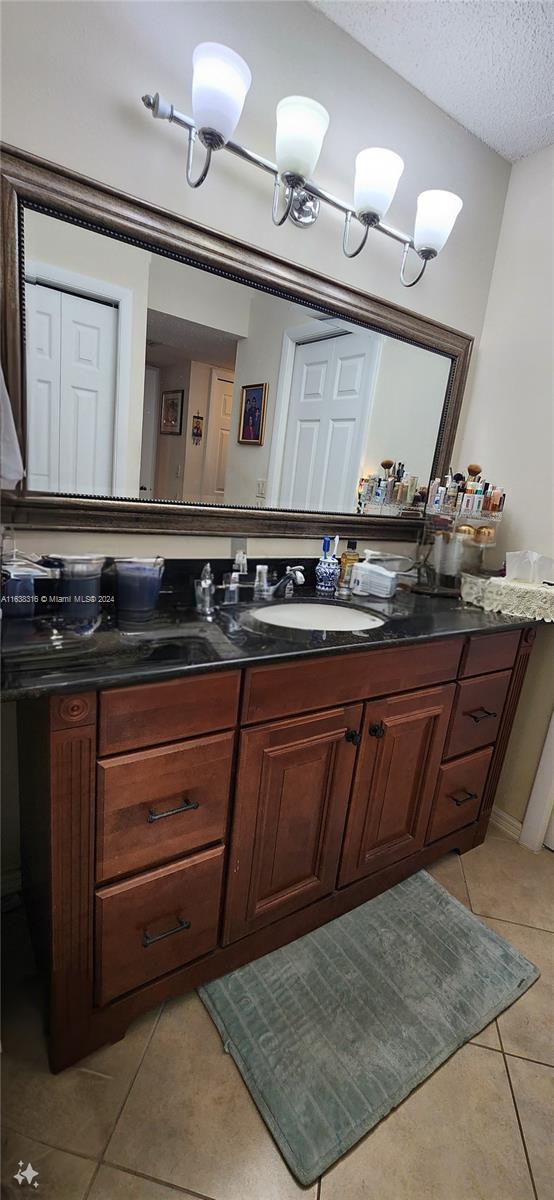 bathroom with vanity, a textured ceiling, and tile patterned flooring