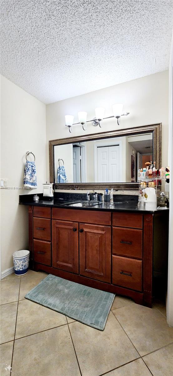 bathroom with tile patterned floors, a textured ceiling, and vanity