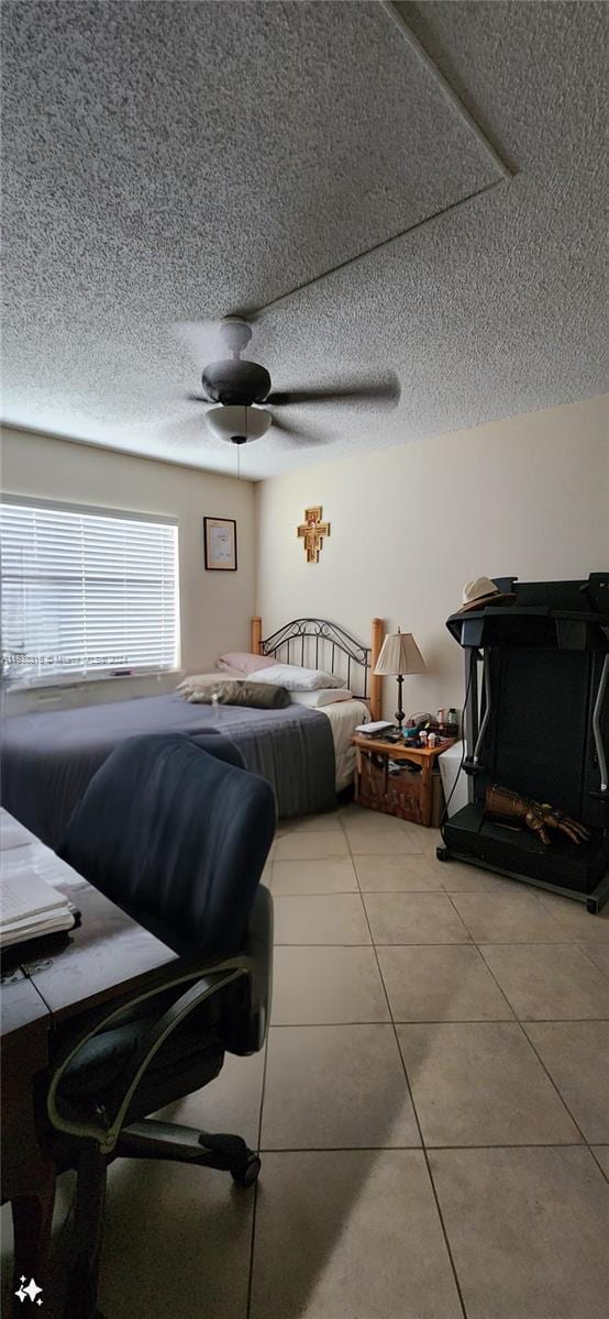 tiled bedroom featuring ceiling fan and a textured ceiling