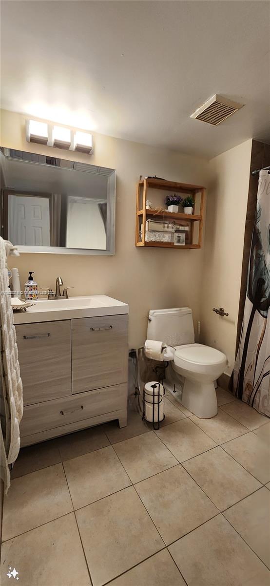 bathroom featuring vanity, toilet, and tile patterned flooring