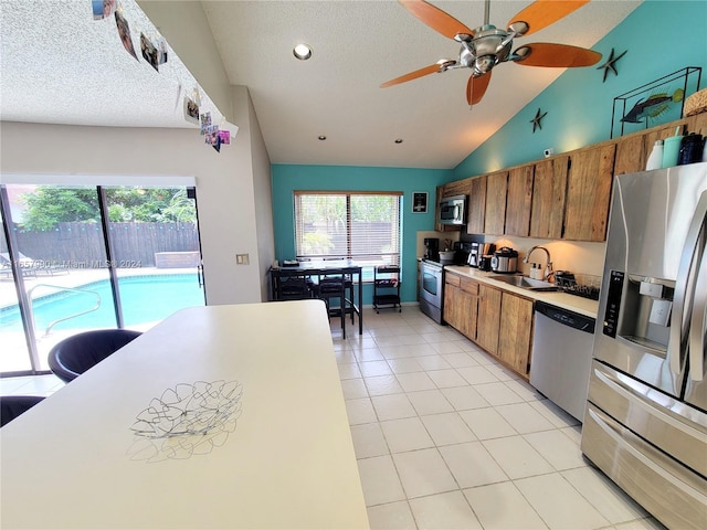 kitchen featuring brown cabinetry, light tile patterned flooring, a sink, stainless steel appliances, and light countertops