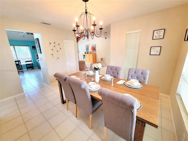 dining area featuring light tile patterned floors, visible vents, ceiling fan with notable chandelier, and baseboards