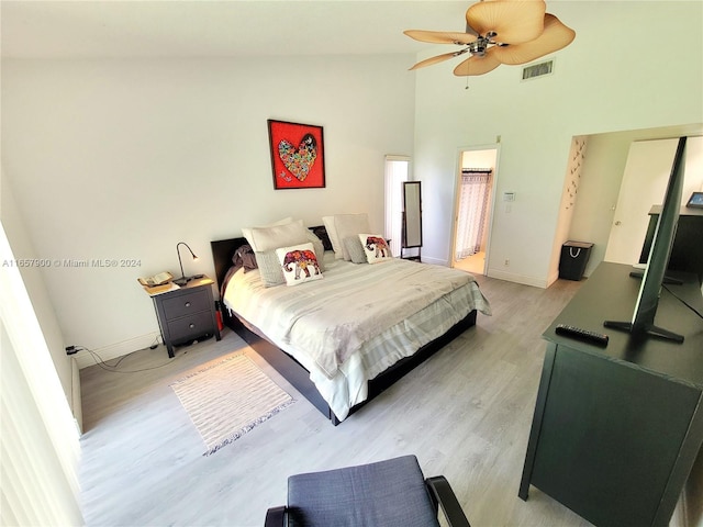 bedroom featuring a ceiling fan, visible vents, baseboards, light wood finished floors, and high vaulted ceiling