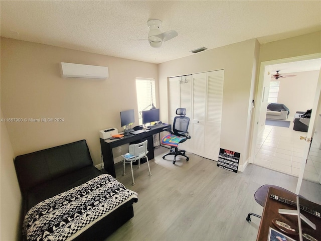 bedroom featuring a wall unit AC, wood finished floors, visible vents, a closet, and a textured ceiling