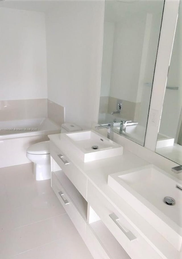 bathroom featuring toilet, vanity, tile patterned flooring, and a tub to relax in