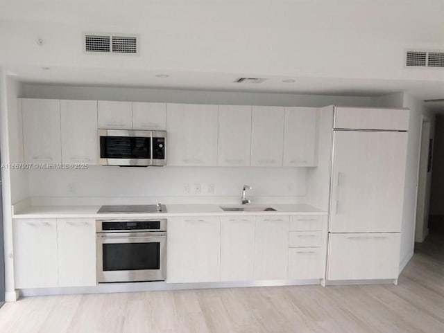 kitchen featuring light hardwood / wood-style floors, sink, white cabinets, and appliances with stainless steel finishes