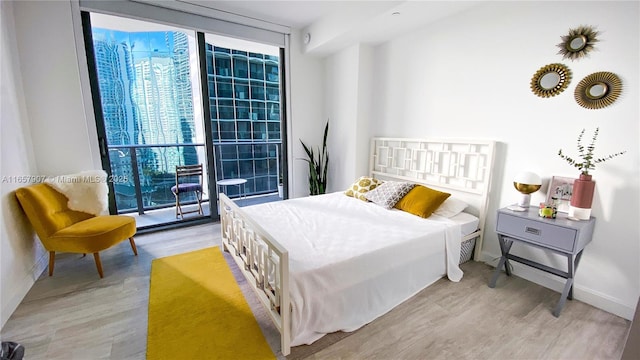 bedroom featuring access to exterior, expansive windows, and light hardwood / wood-style flooring