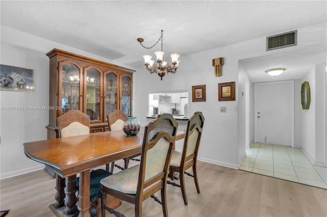 dining room with a chandelier, a textured ceiling, and light hardwood / wood-style flooring