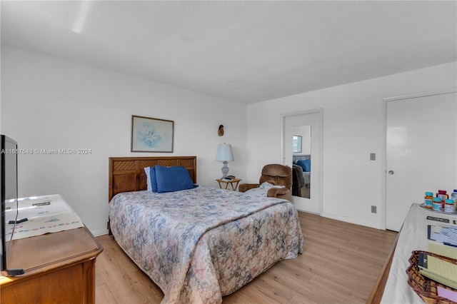 bedroom with light wood-type flooring and a textured ceiling