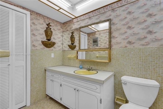 bathroom featuring vanity, toilet, and tile walls