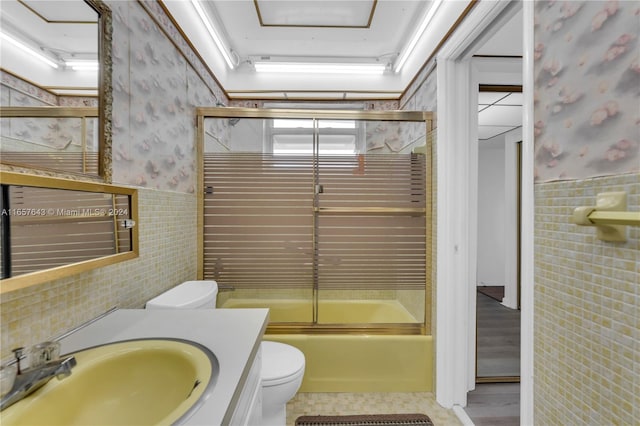 full bathroom with vanity, combined bath / shower with glass door, tile walls, toilet, and hardwood / wood-style flooring