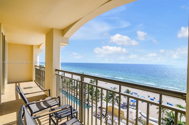 balcony with a water view and a view of the beach