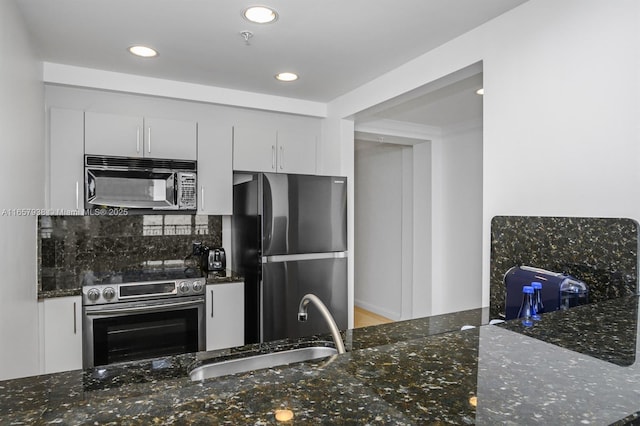 kitchen featuring sink, white cabinetry, refrigerator, electric stove, and dark stone counters