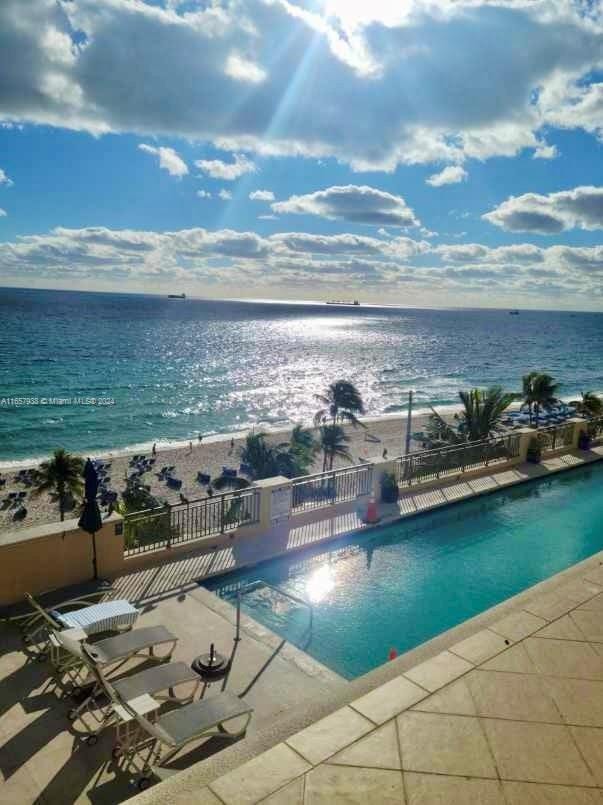 view of swimming pool featuring a patio and a water view