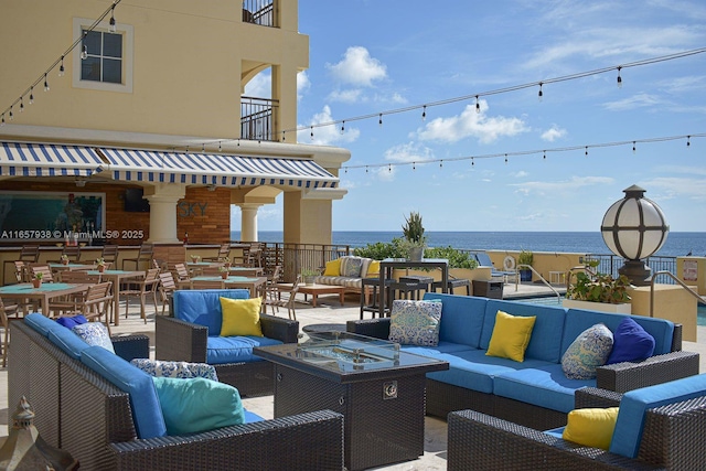 view of patio with an outdoor living space, a balcony, and a water view