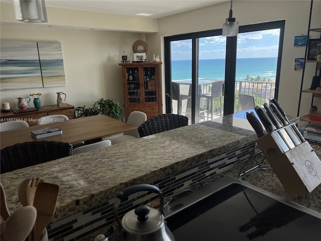 kitchen with a water view, hanging light fixtures, and stone counters