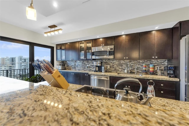 kitchen with pendant lighting, sink, backsplash, dark brown cabinets, and stainless steel appliances