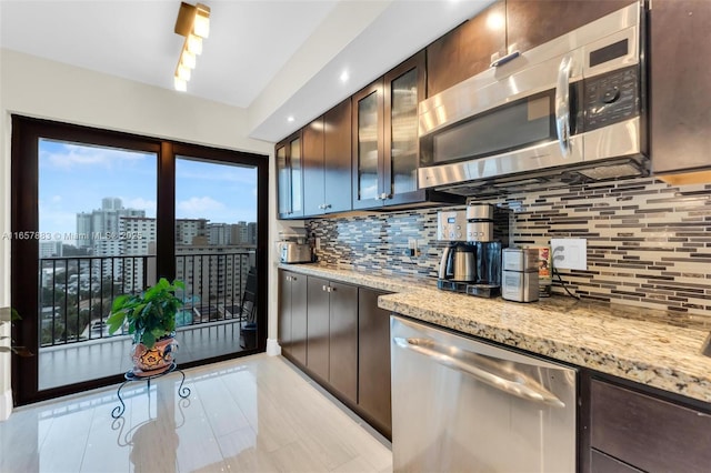 kitchen with tasteful backsplash, light stone countertops, appliances with stainless steel finishes, and dark brown cabinetry