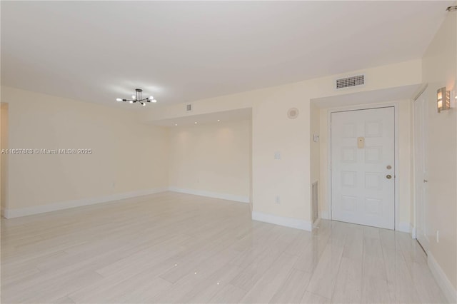 spare room with a notable chandelier and light hardwood / wood-style flooring