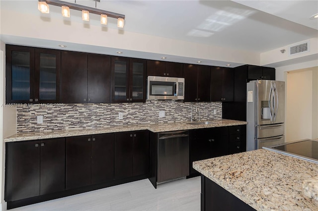 kitchen featuring dark brown cabinetry, stainless steel appliances, sink, and backsplash