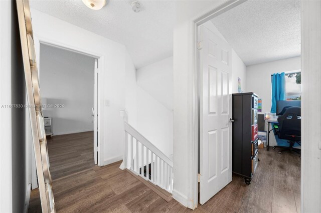 corridor with dark hardwood / wood-style flooring and a textured ceiling