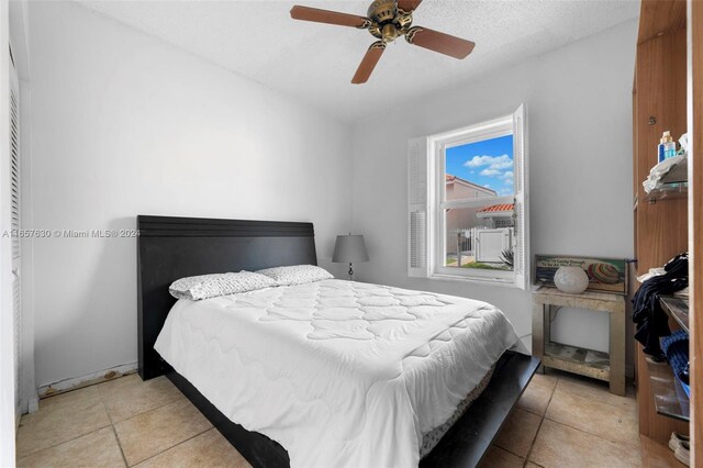 bedroom with a textured ceiling, light tile patterned flooring, and ceiling fan