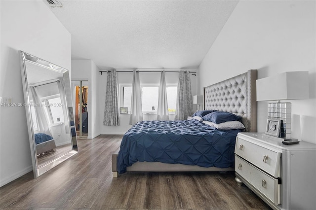 bedroom with vaulted ceiling, dark hardwood / wood-style flooring, and a textured ceiling