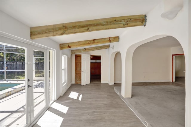 carpeted empty room with french doors and lofted ceiling with beams