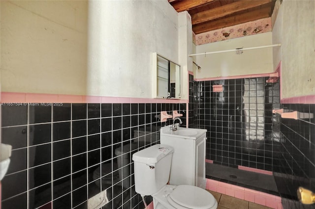 bathroom featuring toilet, vanity, tile walls, tile patterned floors, and tiled shower