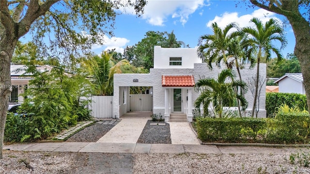 view of front of home featuring a tiled roof, fence, a gate, and stucco siding