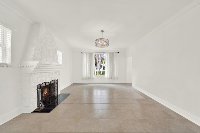 unfurnished living room featuring a chandelier, light tile patterned flooring, baseboards, a lit fireplace, and crown molding