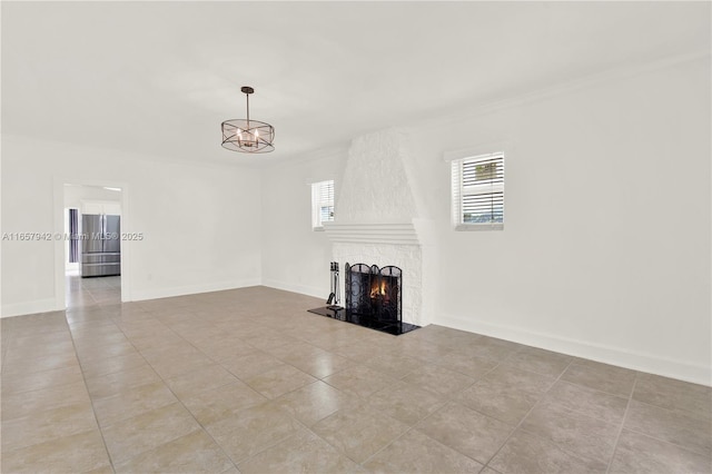 unfurnished living room with a fireplace, baseboards, and an inviting chandelier