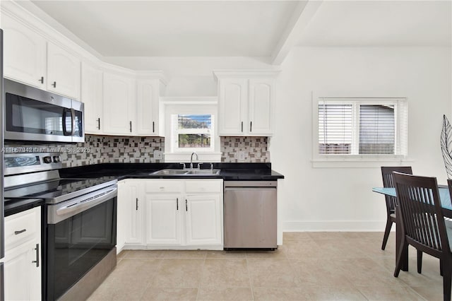 kitchen featuring dark countertops, a sink, stainless steel appliances, white cabinetry, and backsplash