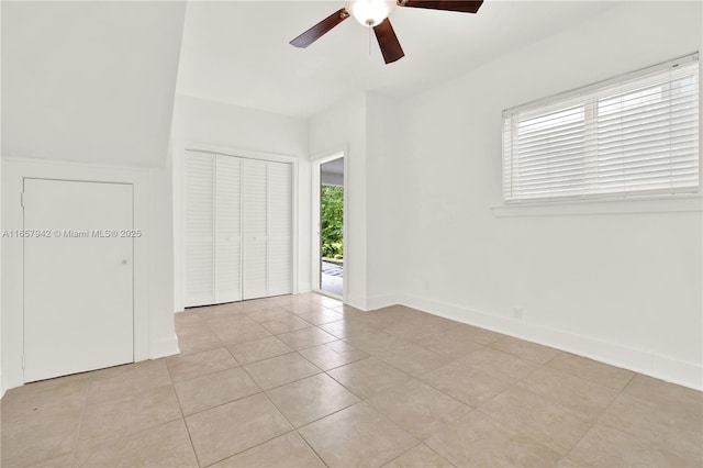 unfurnished bedroom featuring light tile patterned floors, ceiling fan, baseboards, and a closet