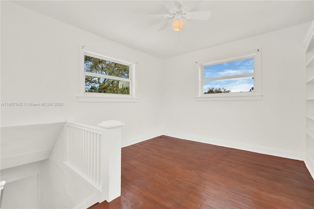 empty room featuring wood-type flooring, a ceiling fan, and baseboards