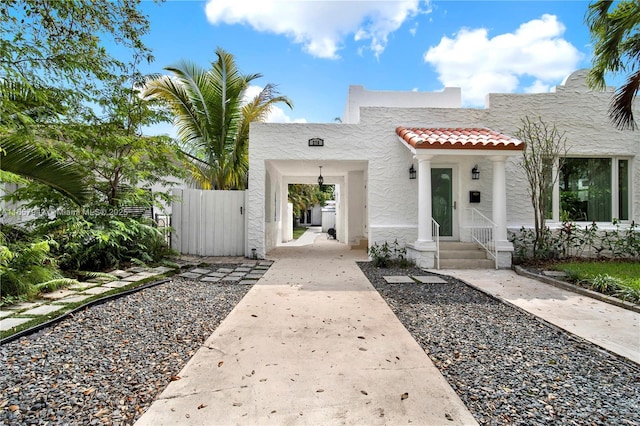 view of front of property with a gate, a tile roof, fence, and stucco siding