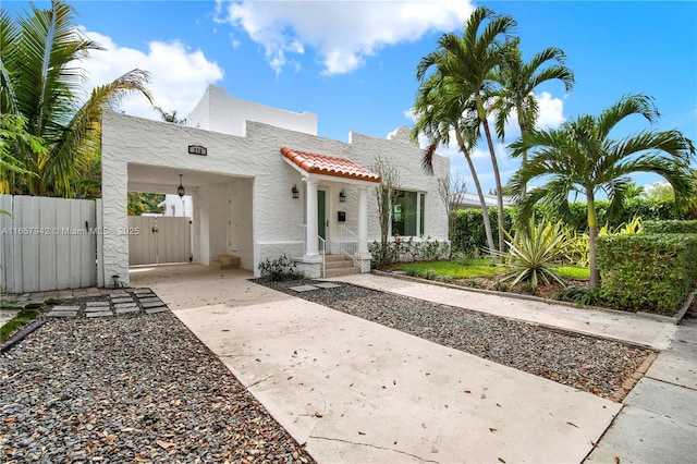 mediterranean / spanish home with stucco siding, concrete driveway, a gate, fence, and a tiled roof